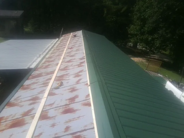 Old rusted panels beside newly installed green metal roofing — Wind Damage Roof Repair by Roofing Brothers in Sunbury